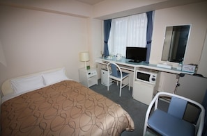 Comfortable retreat with a neatly made bed, compact workspace, and essential amenities.