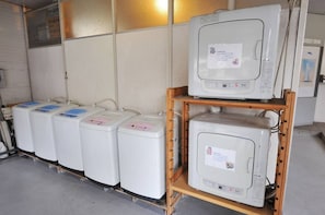 Storage area with a refrigerator and water heaters on wooden shelves.