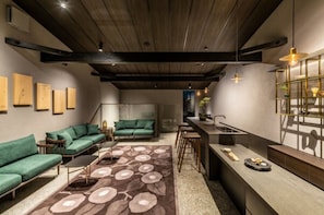 Un interno moderno con soffitto in legno, divani verdi, un tappeto decorato e un angolo bar.