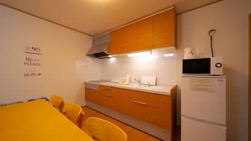 Een koelkast, een magnetron, kookgerei, borden en bestek