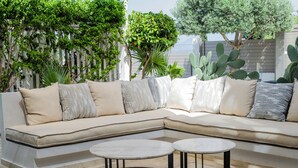 Ein modulares Sofa mit vielen Kissen, zwei runden Tischen und verschiedenen Pflanzen.