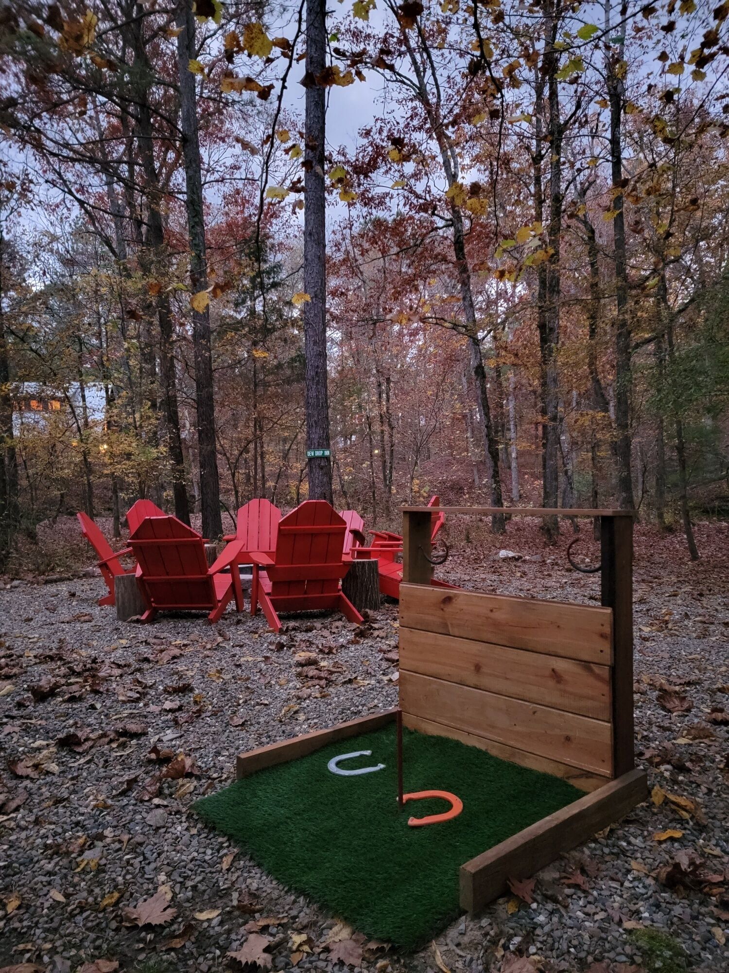 Ein bewaldetes Gebiet mit einer kleinen Holzhütte und roten Adirondack-Stühlen.
