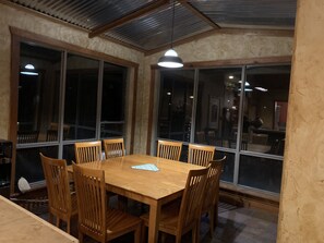 Enjoy meals in this dining area with a large table and six chairs, surrounded by large windows and pendant lights.