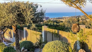 Ein Garten mit vielfältigen Pflanzen, einem Kiesweg und Blick auf das Meer.