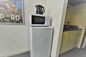 Compact kitchen with microwave, coffee maker, and refrigerator, perfect for small living spaces.