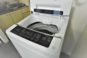 Convenient kitchenette with a modern washing machine and digital controls.