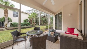 A covered patio with wicker furniture, a glass table, and a ceiling fan. - Spacious 2 bedroom+ den condo in Arielle on Palmer Ranch condominiums for rent (Sarasota)