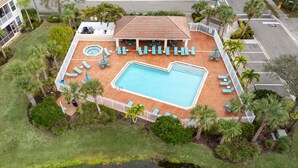 An aerial view of a resort with a swimming pool, lounge chairs, and palm trees. - Spacious 2 bedroom+ den condo in Arielle on Palmer Ranch condominiums for rent (Sarasota)