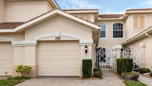 A beige two-story house with a garage number 6965, a gated entrance, and a paved driveway. - Spacious 2 bedroom+ den condo in Arielle on Palmer Ranch condominiums for rent (Sarasota)