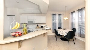 A compact kitchen with a microwave, stove, and a fruit bowl on the counter. - Spacious 2 bedroom+ den condo in Arielle on Palmer Ranch condominiums for rent (Sarasota)
