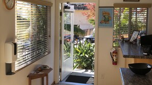A kitchen with a door leading outside, a clock on the wall, and a framed picture of a delivery truck. - Moonlight Beach Motel (Encinitas)