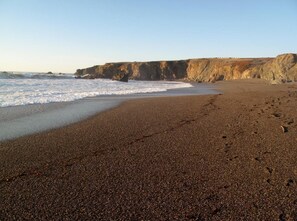 A beach with a rocky cliff in the background.