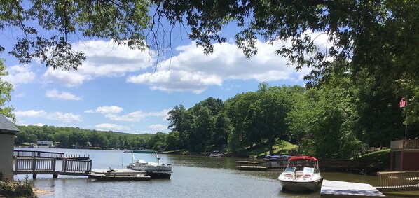 A lakeside dock with boats, a wooden pier, and a building with a flag.