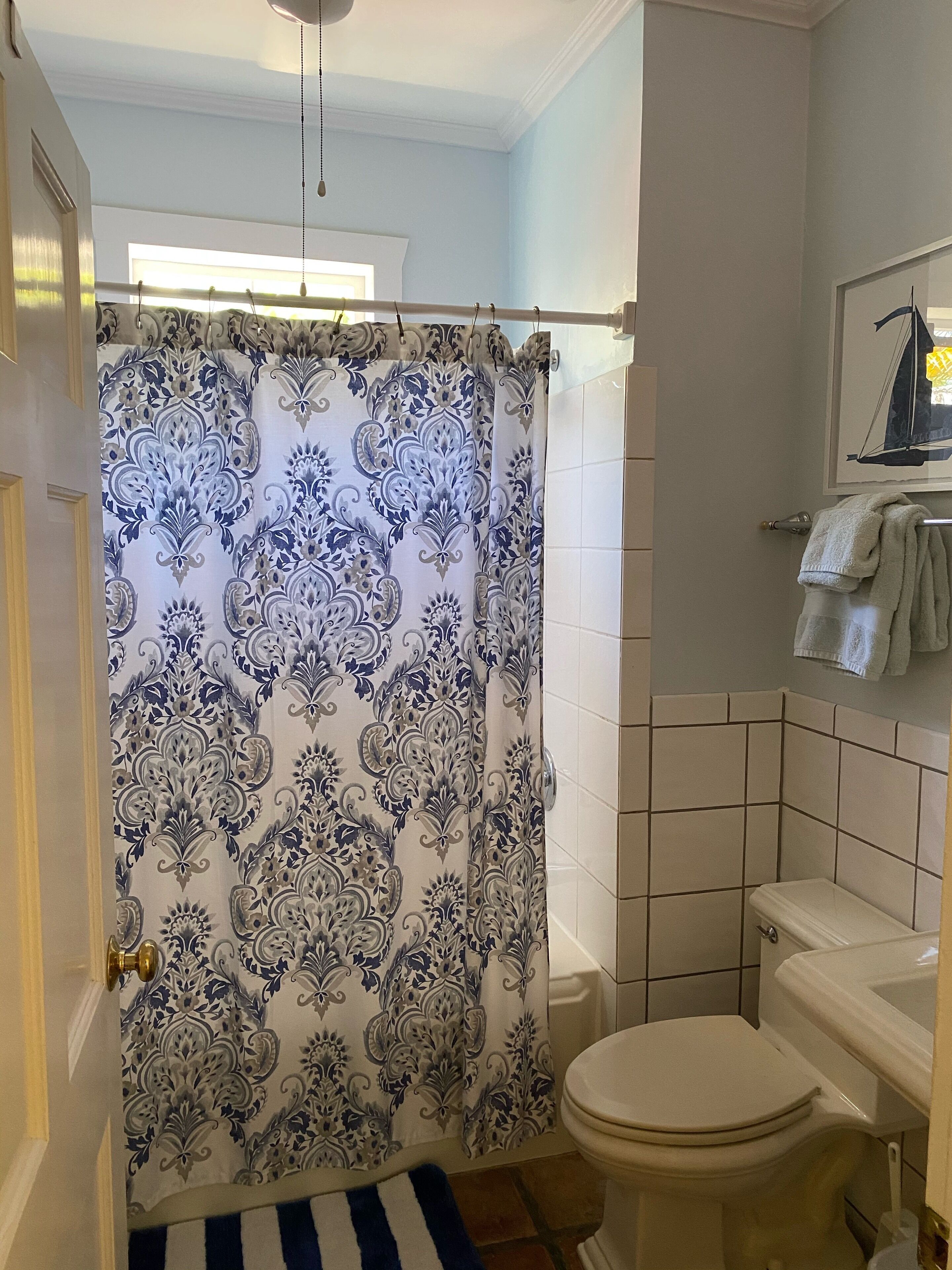 A bathroom with a patterned shower curtain, a toilet, and a tiled wall.