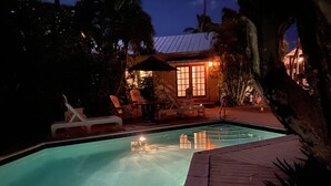 Une piscine avec des chaises longues et un petit bâtiment doté d’une véranda.