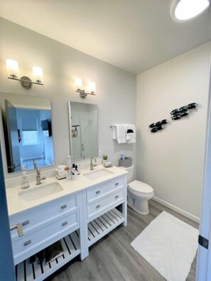 Un baño moderno con tocador doble, inodoro y zona de ducha.