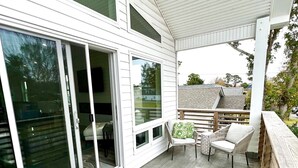 A covered patio with wicker furniture and a wooden deck. - MODERN Beach Home! Dogs Welcome! 6 Passenger Golf Cart & Free Town of CB Parking (Carolina Beach)