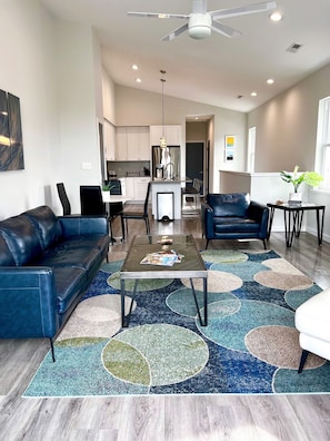 A modern living room with a glass coffee table, two sofas, and a patterned rug.