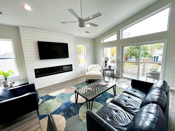A modern living room with a flat-screen TV, leather sofa, and a patterned rug.