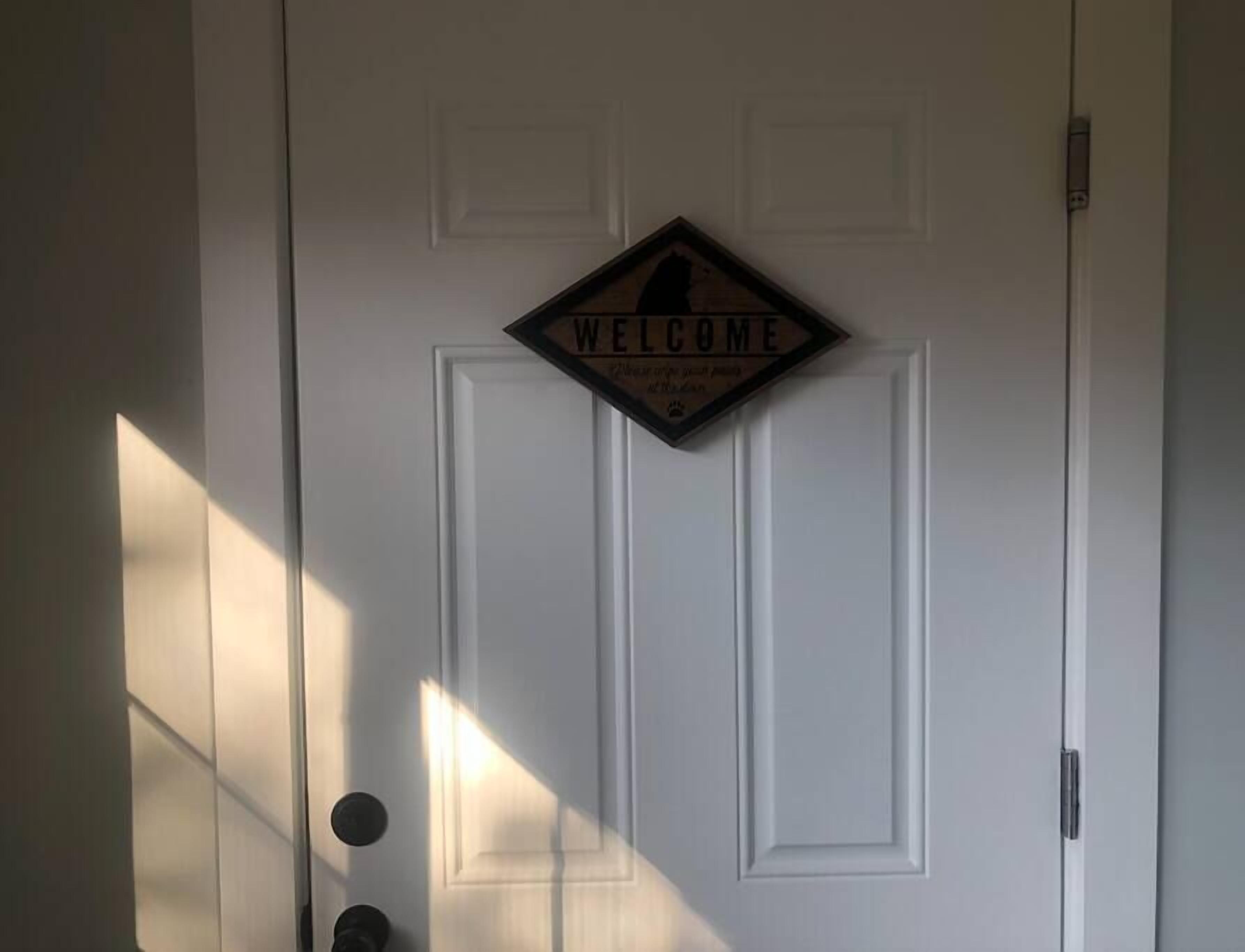 Eine weiße Tür mit einem 'WELCOME'-Schild und Pfotenabdruck.