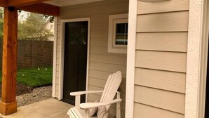 A covered porch with a white Adirondack chair, a wooden beam ceiling, and a hanging light fixture. - *Sandpoint Cottage* Cozy, Charming, & Conveniently located (Sandpoint)