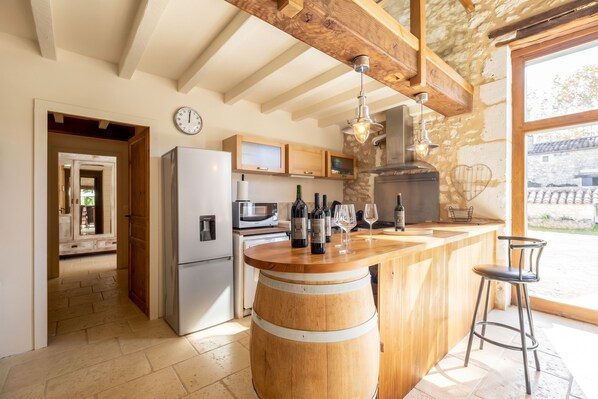 A modern kitchen with a wooden island, stainless steel appliances, and a stone wall.