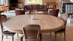 A rustic interior with a stone wall, wooden ceiling beams, a round dining table, and a fireplace. - Homerez - "Sigoulès villa with pool" (Sigoulès)
