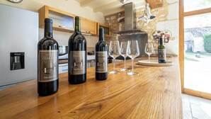 Una barra de madera con tres botellas de vino y cuatro copas.