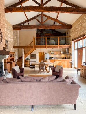 A spacious living area with a large sofa, a dining table, and a kitchen in the background. - Homerez - "Sigoulès villa with pool" (Sigoulès)