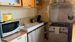 A compact kitchen with a microwave, toaster, and gas stove. - Homerez - "Sigoulès villa with pool" (Sigoulès)