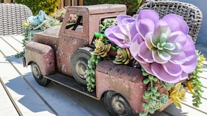 Camioneta antigua decorada con suculentas y flores estacionada en un porche.