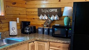 A kitchen with wooden cabinets, a coffee maker, a microwave, and a refrigerator.