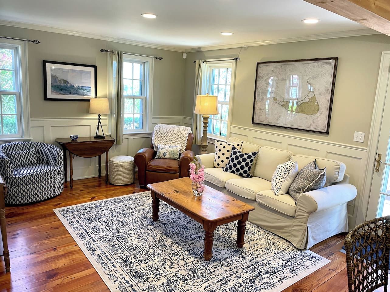 A living room with a wooden coffee table, a patterned rug, a sofa, a patterned armchair, and a side table with a lamp.
