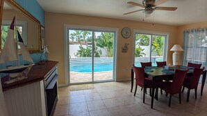 A dining area with a view of a swimming pool, a ceiling fan, and a clock on the wall. - Tropical paradise! Spa, heated pool, 2 miles from Siesta Key beach, very private (Sarasota)