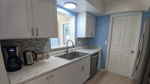 A kitchen with white cabinets, a marble countertop, a stainless steel sink, a coffee maker, and a dishwasher. - Tropical paradise! Spa, heated pool, 2 miles from Siesta Key beach, very private (Sarasota)