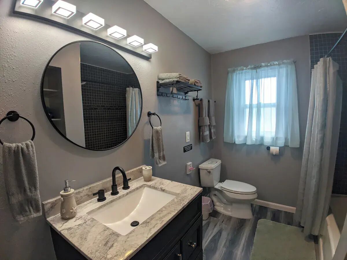 Une salle de bain équipée d’un lavabo, d’un miroir, de toilettes et d’un rideau de douche.