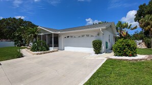 A single-story house with a covered porch, a garage, and a well-maintained lawn. - Tropical paradise! Spa, heated pool, 2 miles from Siesta Key beach, very private (Sarasota)