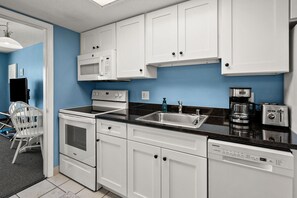 A kitchen with white cabinets, a microwave, a stove, a sink, and a dishwasher.