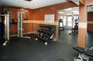 A gym with weightlifting equipment, treadmills, and a sign indicating it is a fitness center.