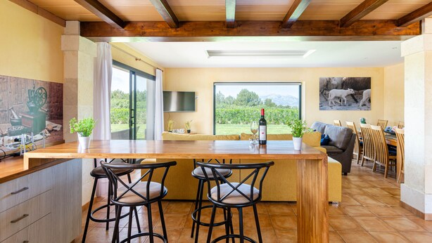 A spacious kitchen with a large island, bar stools, and a dining area with wooden chairs and a table. - YourHouse Villa Romani con piscina privada y jardín (Muro)