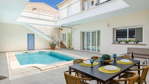A poolside dining area with a table set for two, a staircase, and a view of the pool. - Casa moderna con piscina privada y barbacoa, YourHouse Villa Marian (Muro)