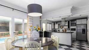 A modern kitchen with a central island, a dining area with a round table and chairs, and a view of a pool. - Casa moderna con piscina privada y barbacoa, YourHouse Villa Marian (Muro)