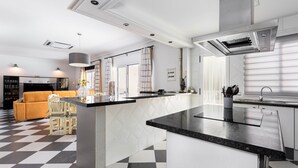 A modern kitchen with a black and white checkered floor, a central island, and a dining area with a yellow sofa and white chairs. - Casa moderna con piscina privada y barbacoa, YourHouse Villa Marian (Muro)