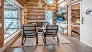 A log cabin interior with a dining area, large windows, and a fireplace. - Villa rytilampi b by Interhome (Kuusamo)
