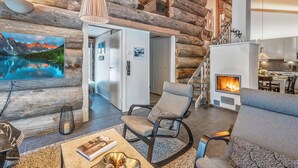 A log cabin interior with a fireplace, modern furniture, and a large TV displaying a mountain landscape. - Villa rytilampi b by Interhome (Kuusamo)