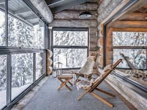 A cozy cabin interior with large windows, a fireplace, and a comfortable seating area. - Villa rytilampi b by Interhome (Kuusamo)