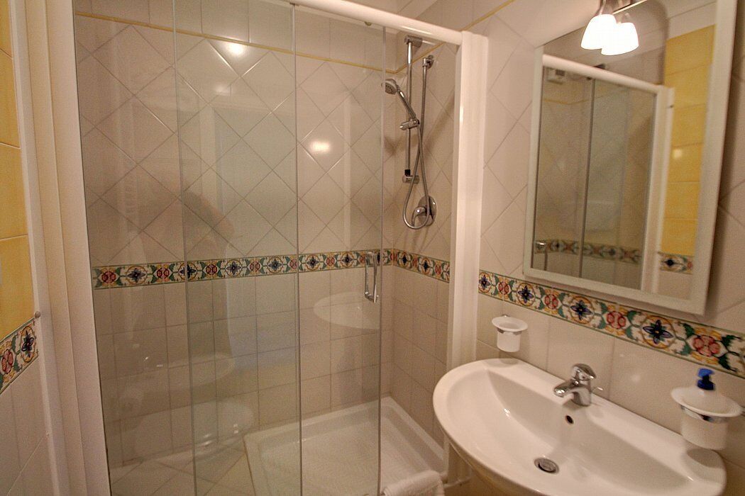 A bathroom with a glass-enclosed shower, a sink, and a mirror.