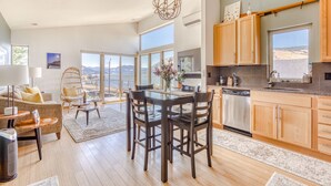 A spacious living area with a dining table, chairs, and a view of the mountains through large windows. - All About the View - Walk to River, Town, & Trails in Quaint Mosier (Mosier)