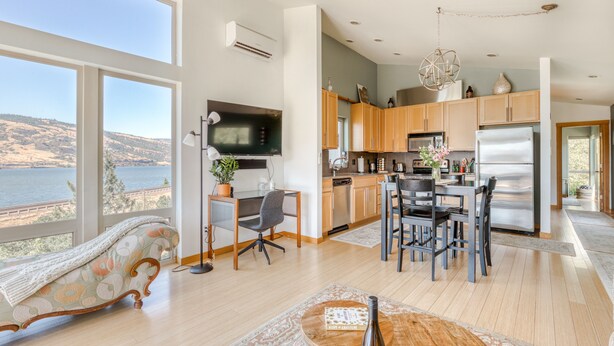 A modern kitchen with a large island, wooden cabinets, and a view of the lake. - All About the View - Walk to River, Town, & Trails in Quaint Mosier (Mosier)