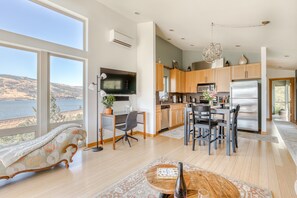 A modern kitchen with a large island, wooden cabinets, and a view of the lake. - All About the View - Walk to River, Town, & Trails in Quaint Mosier (Mosier)